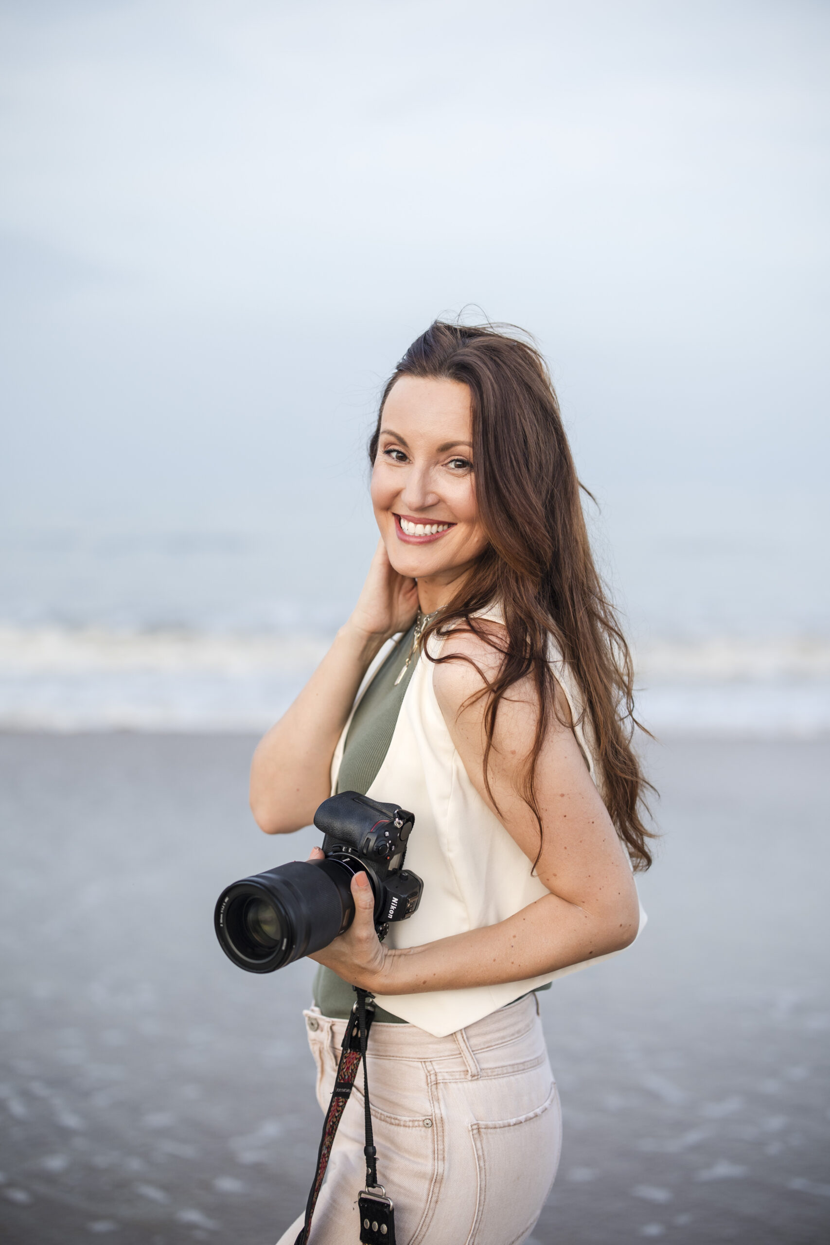 Jacksonville photographer portrait of herself holding camera during sunset beach branding session at Ponte Vedra Beach