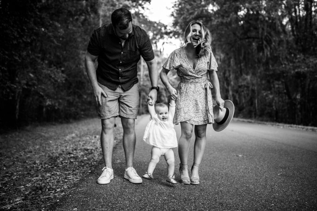 Full of joy capture of family of three in the Jacksonville park while mom and dad are swinging their toddler girl