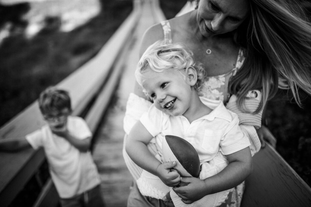 Momma tickling her son to get his football during their Neptune Beach family session by Jacksonville photographer