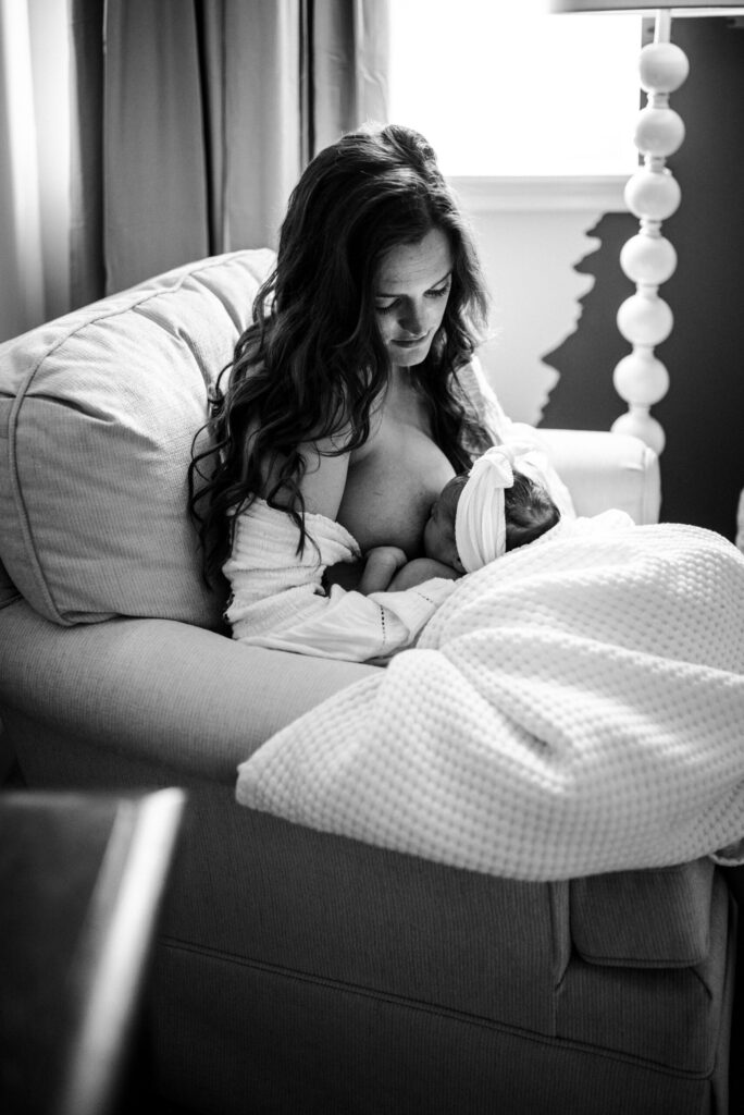 Emotive black and white image of a mother breastfeeding her newborn in the rocking chair, captured by a Jacksonville newborn photographer