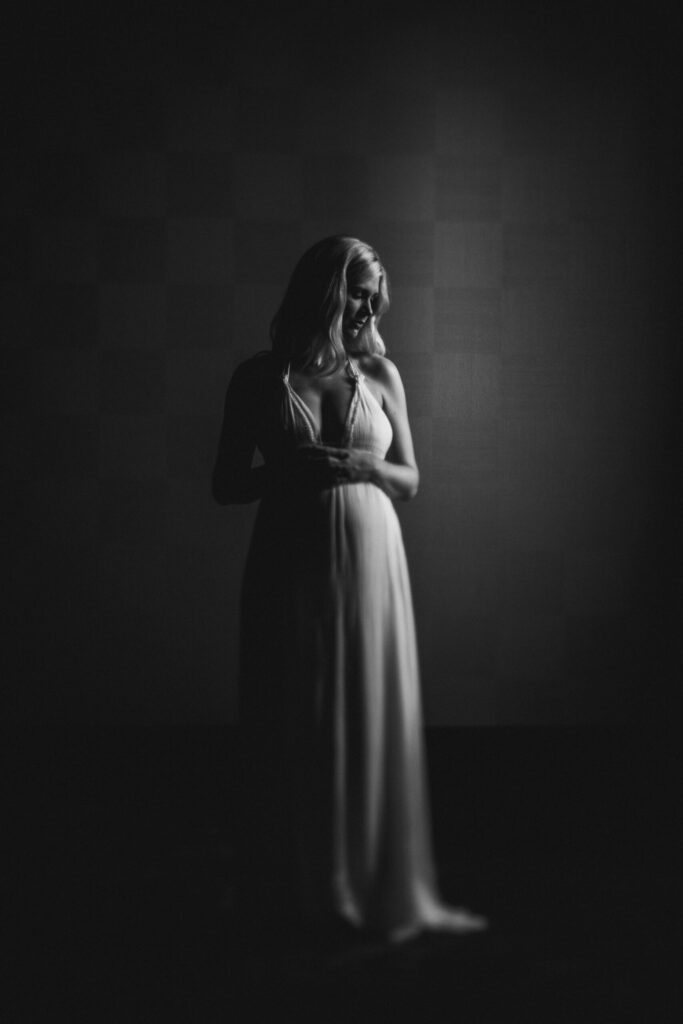 deep shadows black and white indoor maternity portrait showcasing shape of mommas belly by Jacksonville maternity photographer