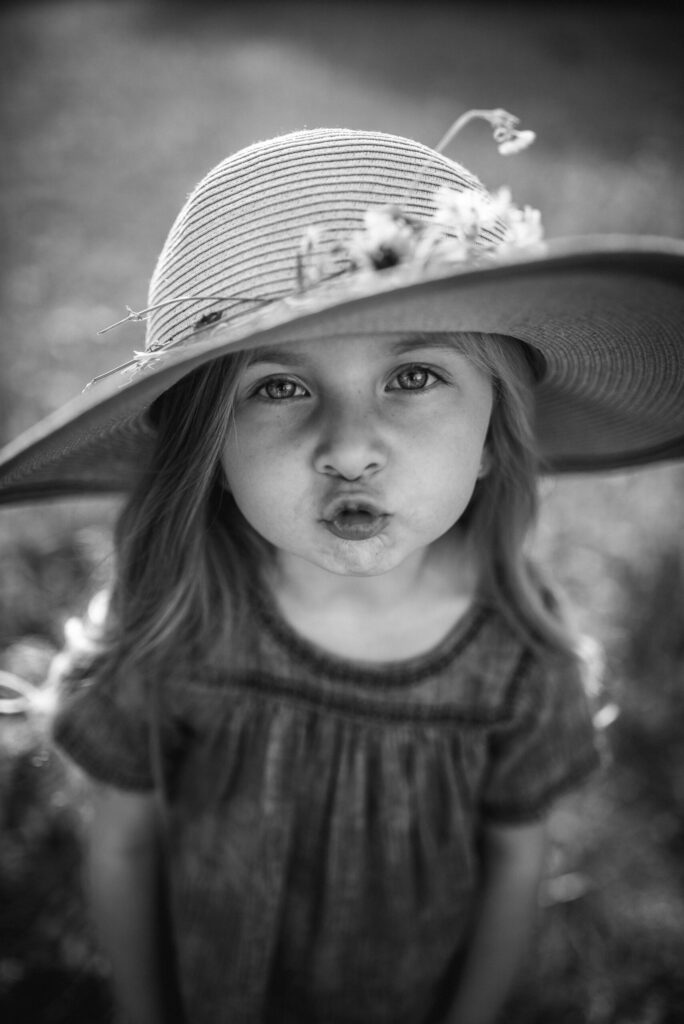 portrait of little girl sending a kiss in her flower field session by Jacksonville family photographer