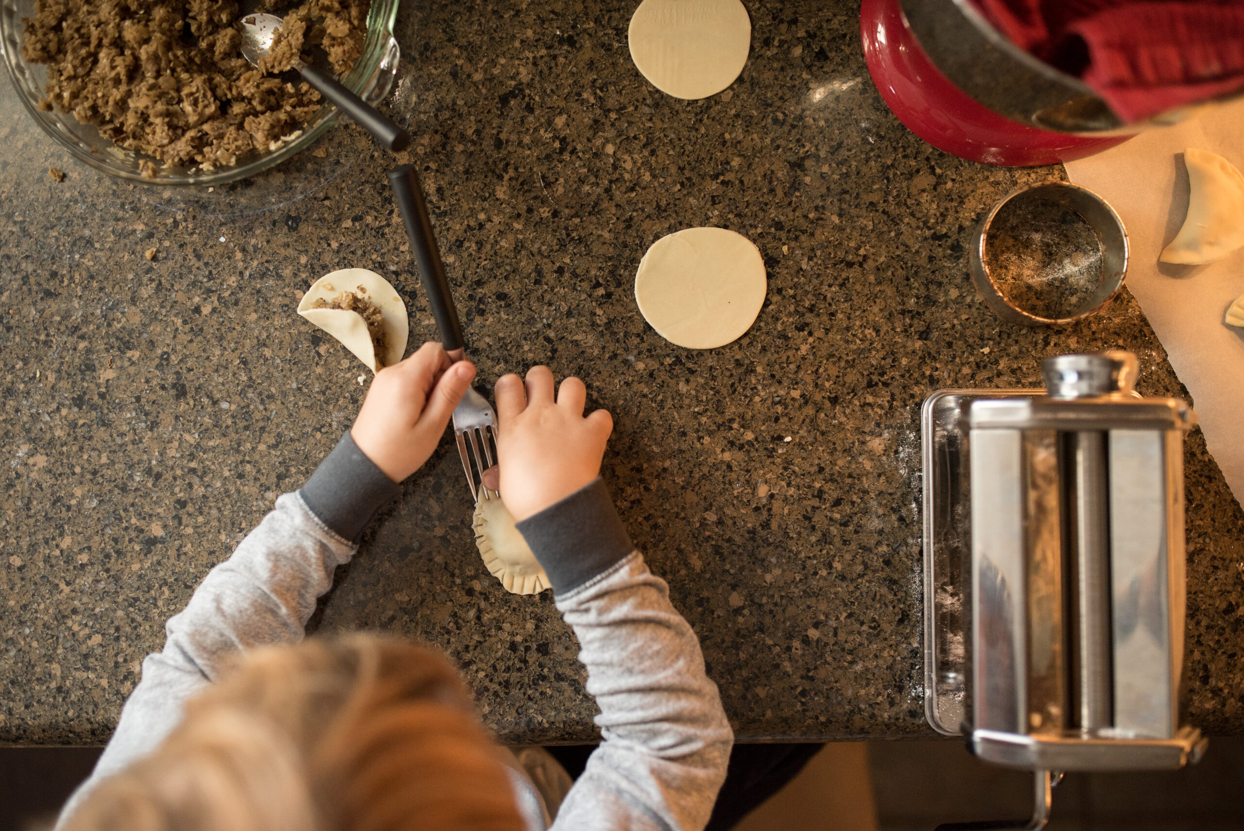 wide angle photo of little boy making pierogies on kitchen counterop