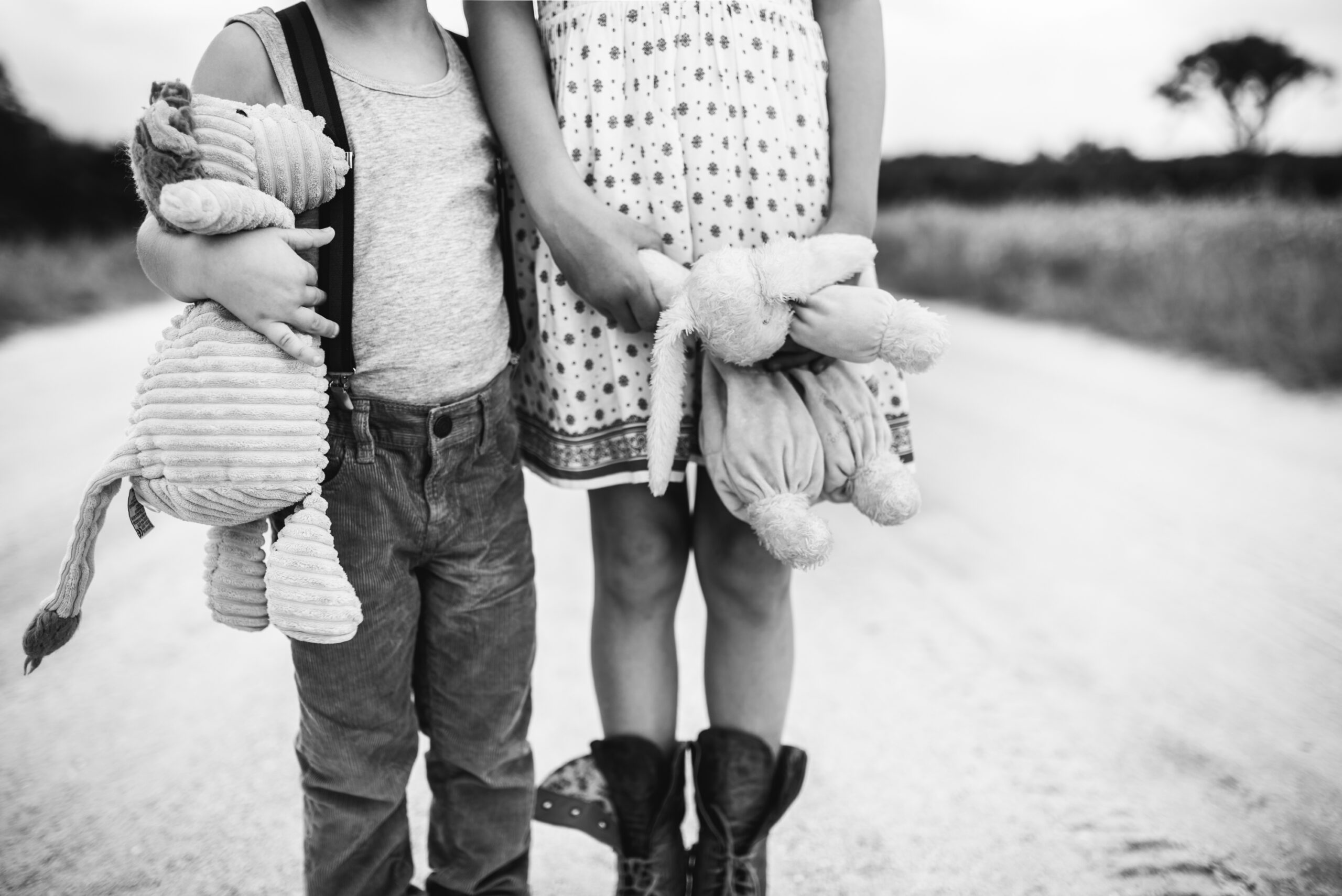 black and white photo of two kids holding their stuffed animals while standing in the dirt road on Ponte Vedra Guana park