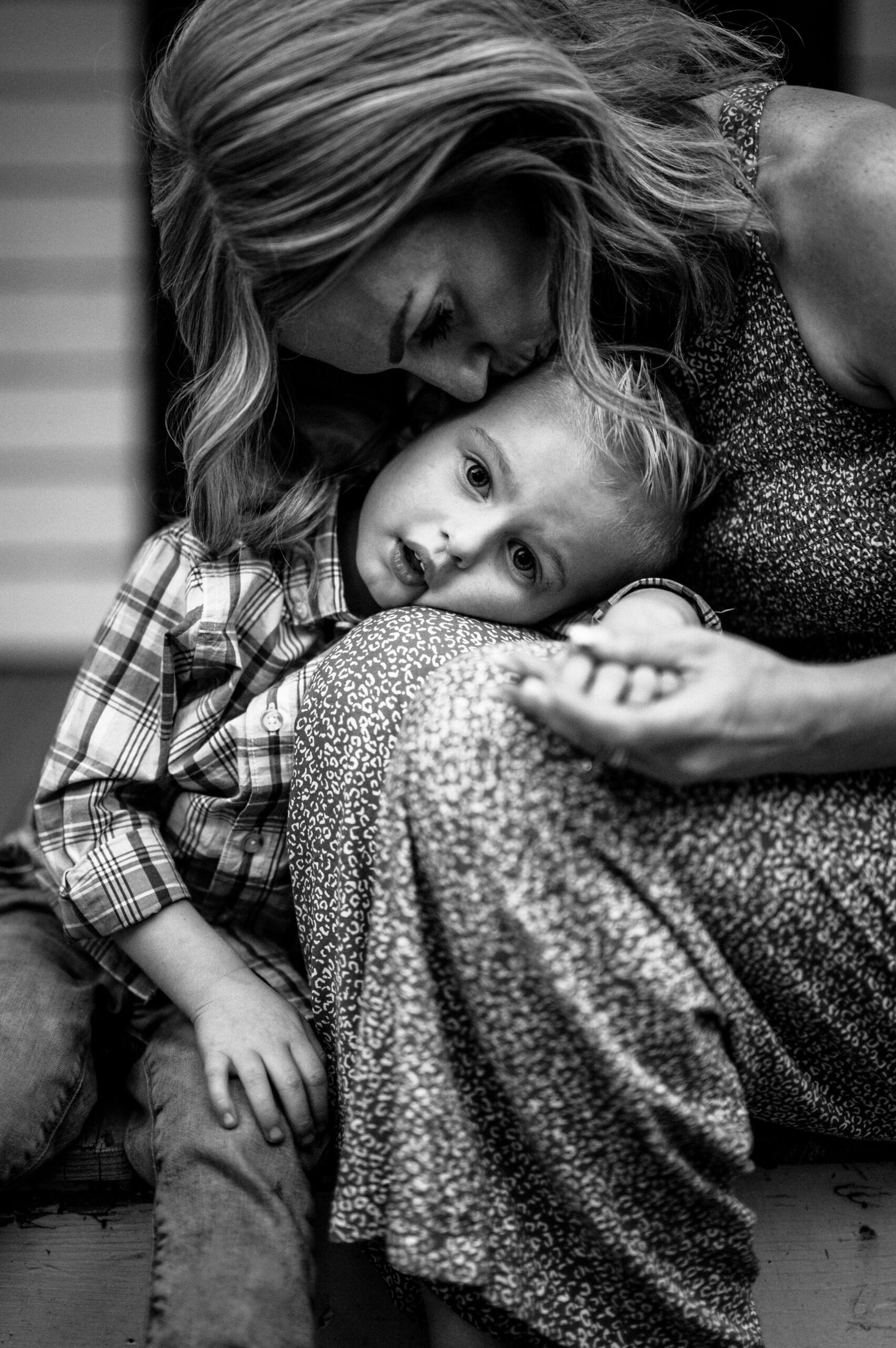 mother kissing young child while they rest on her knee in a Jacksonville children's photoshoot
