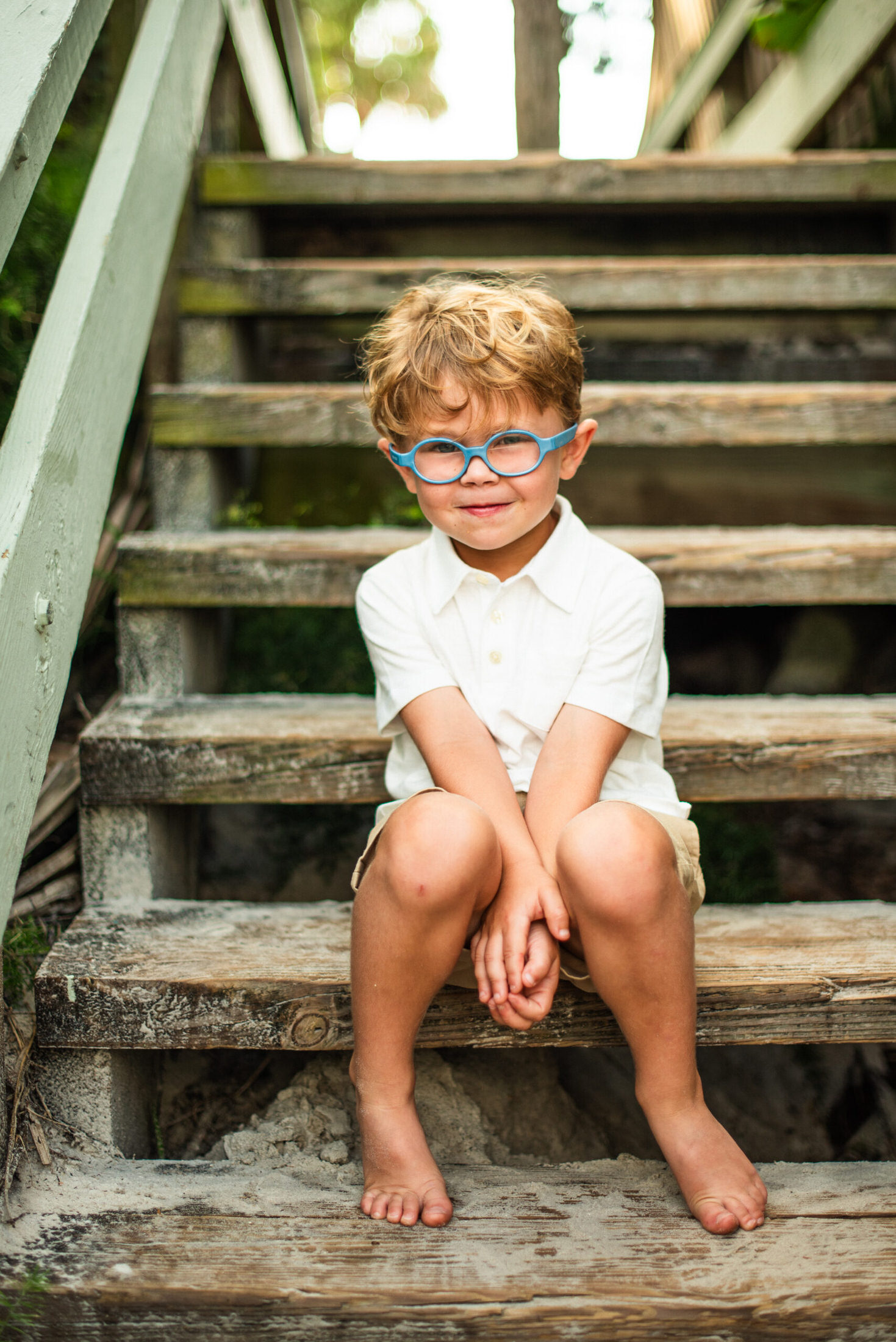 young child with glasses sitting on the steps posing for a photo in a Jacksonville children's photoshoot