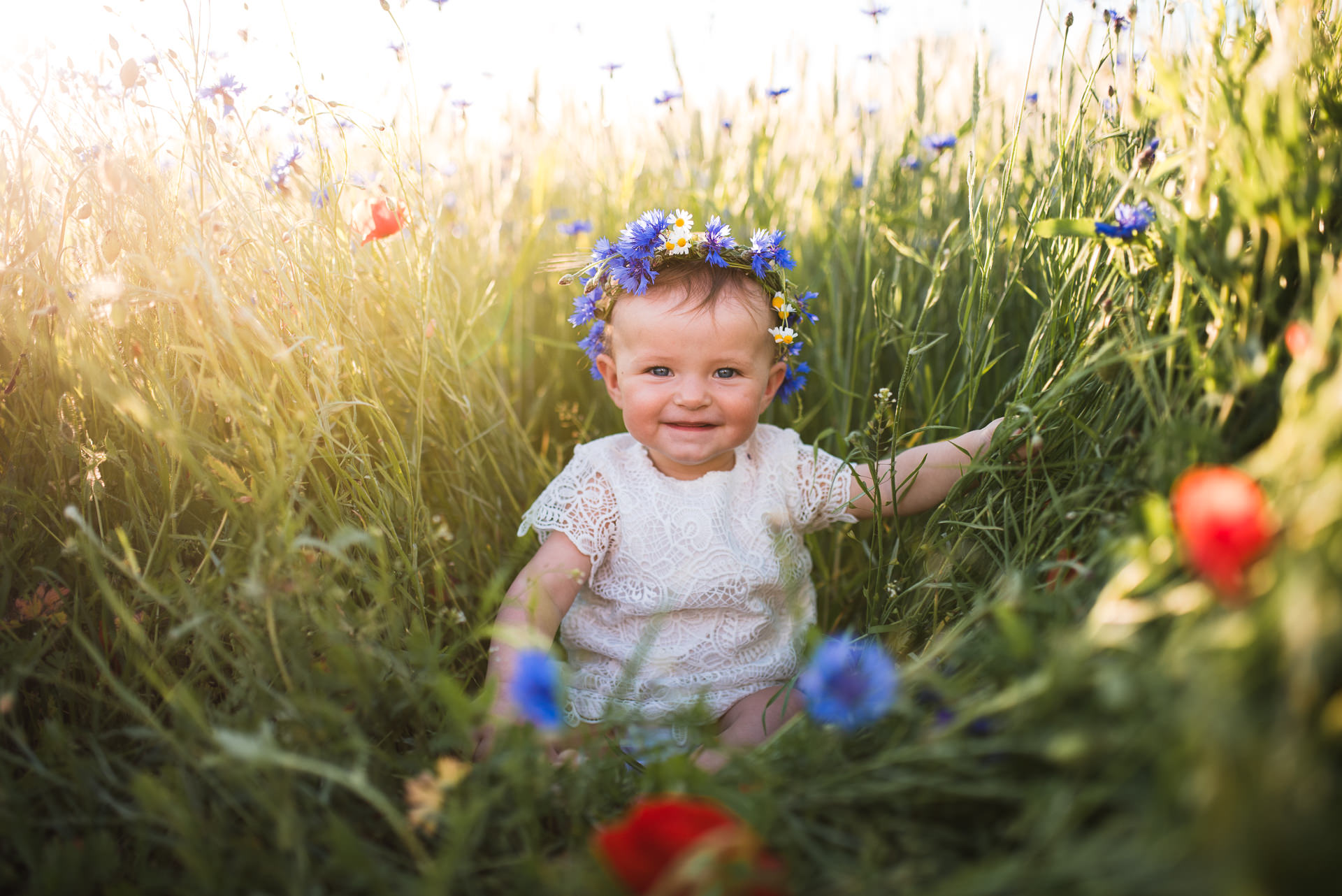 baby smiling in a field of flowers wearing flower grown in a Jacksonville children's photoshoot