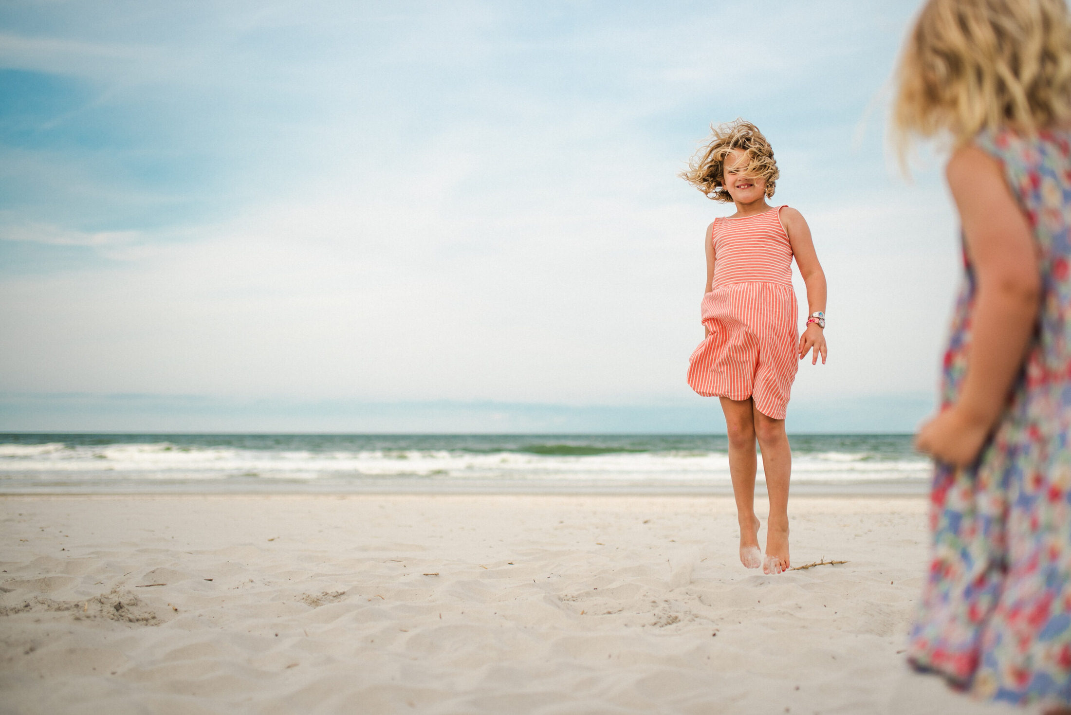 two young children running playing on the beach in a Jacksonville children's photoshoot