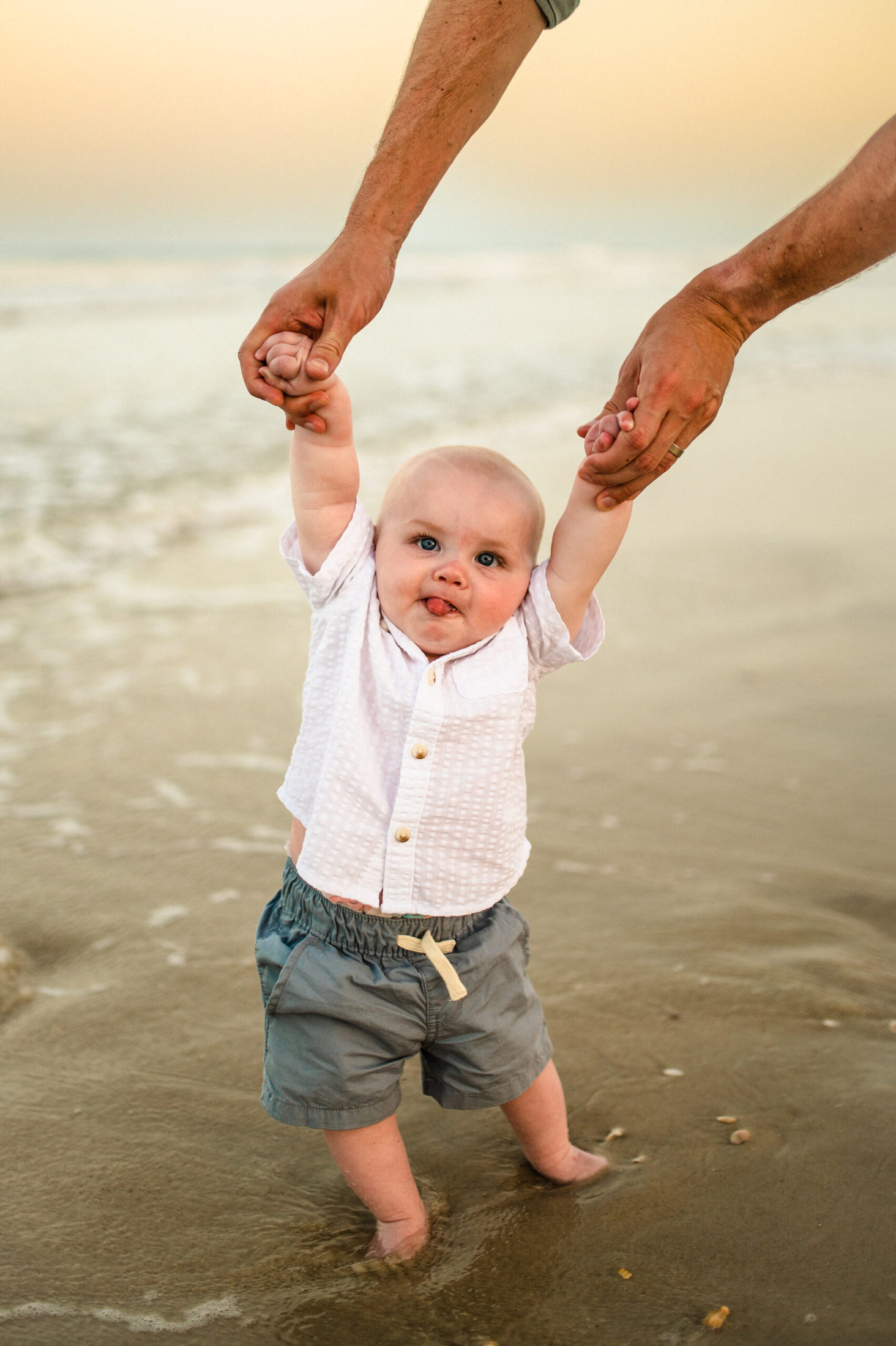 baby being held up by parent on the beach shore Jacksonville children's photoshoot