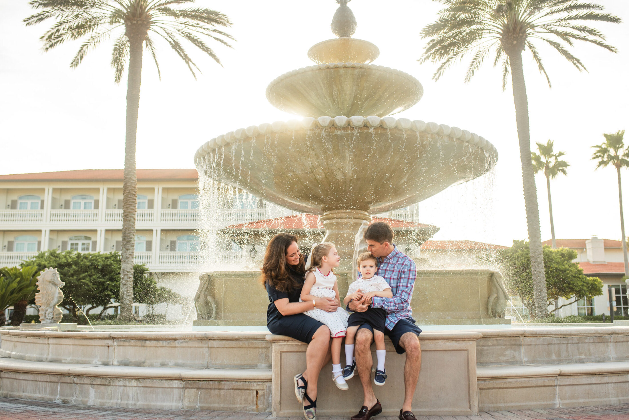 Parents and children sitting on a fountain smiling at each other in a family photoshoot in Jacksonville FL