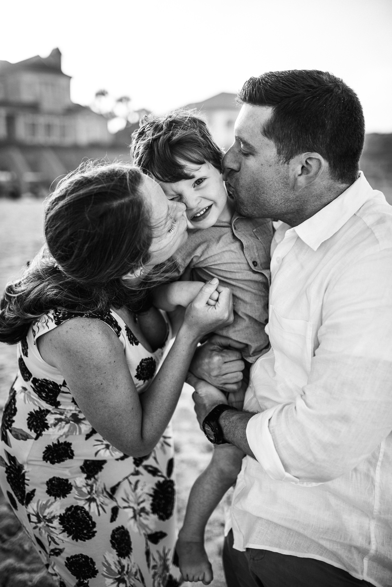 Parents kissing their small child at the same time posing for photo in a family photoshoot in Jacksonville FL