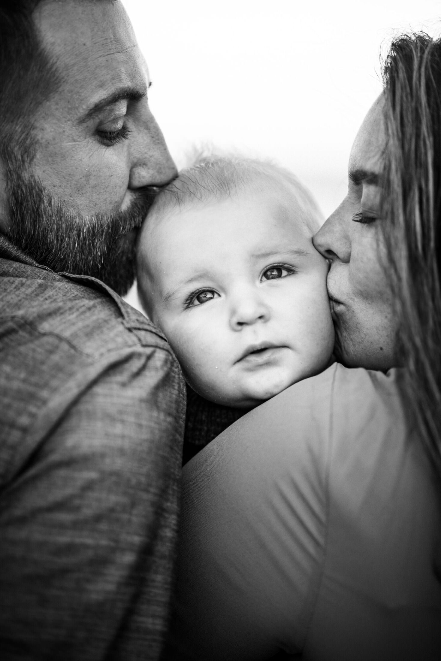 Close up of parents kissing baby at the same time in a family photoshoot in Jacksonville FL