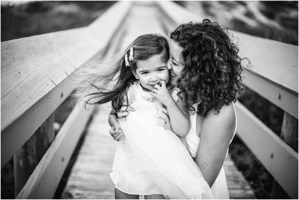 Mother holding and kissing small child on their cheek in a family photoshoot in Jacksonville FL