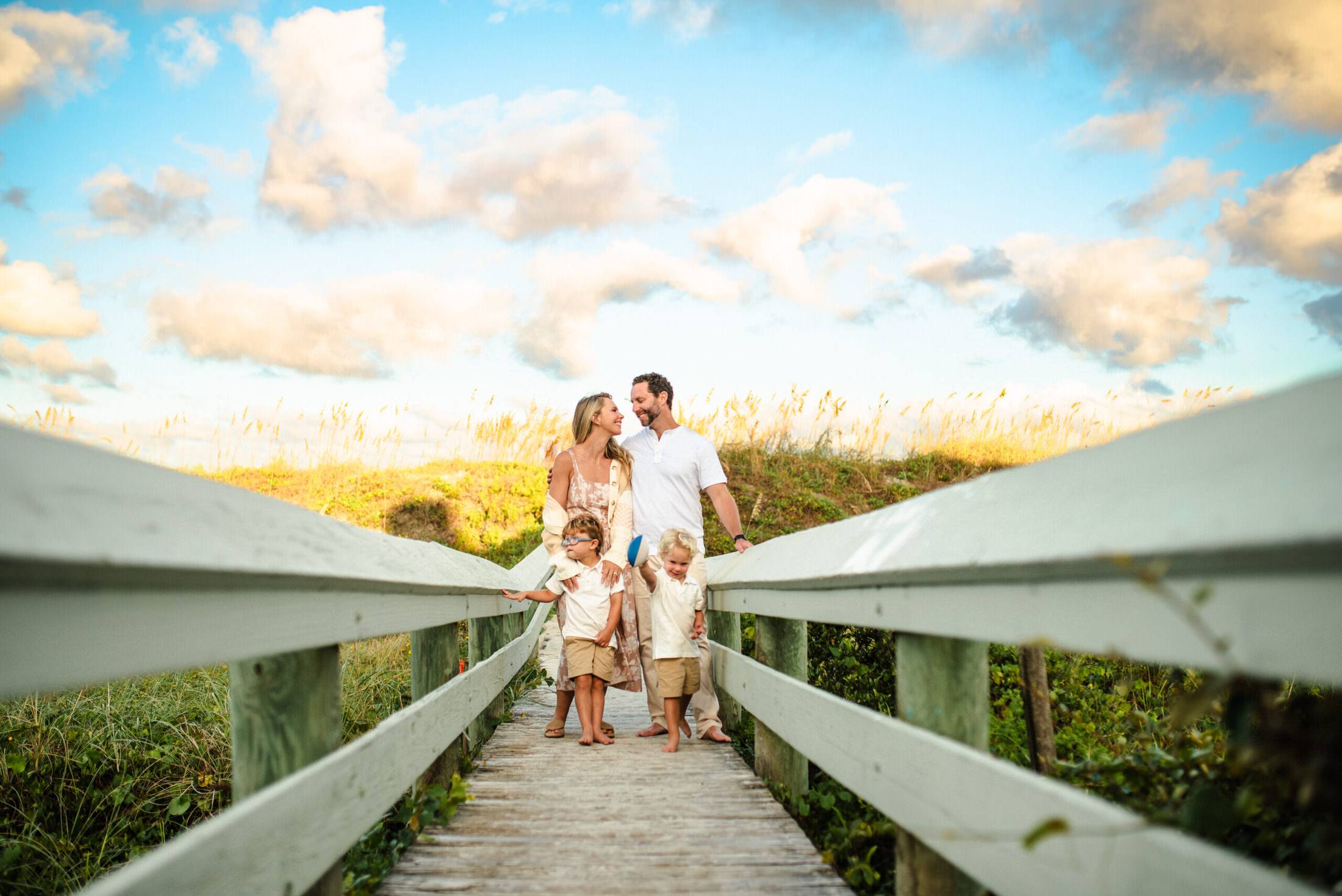 Parents and children posing for a family photo on the beach boardwalk in a family photoshoot in Jacksonville FL