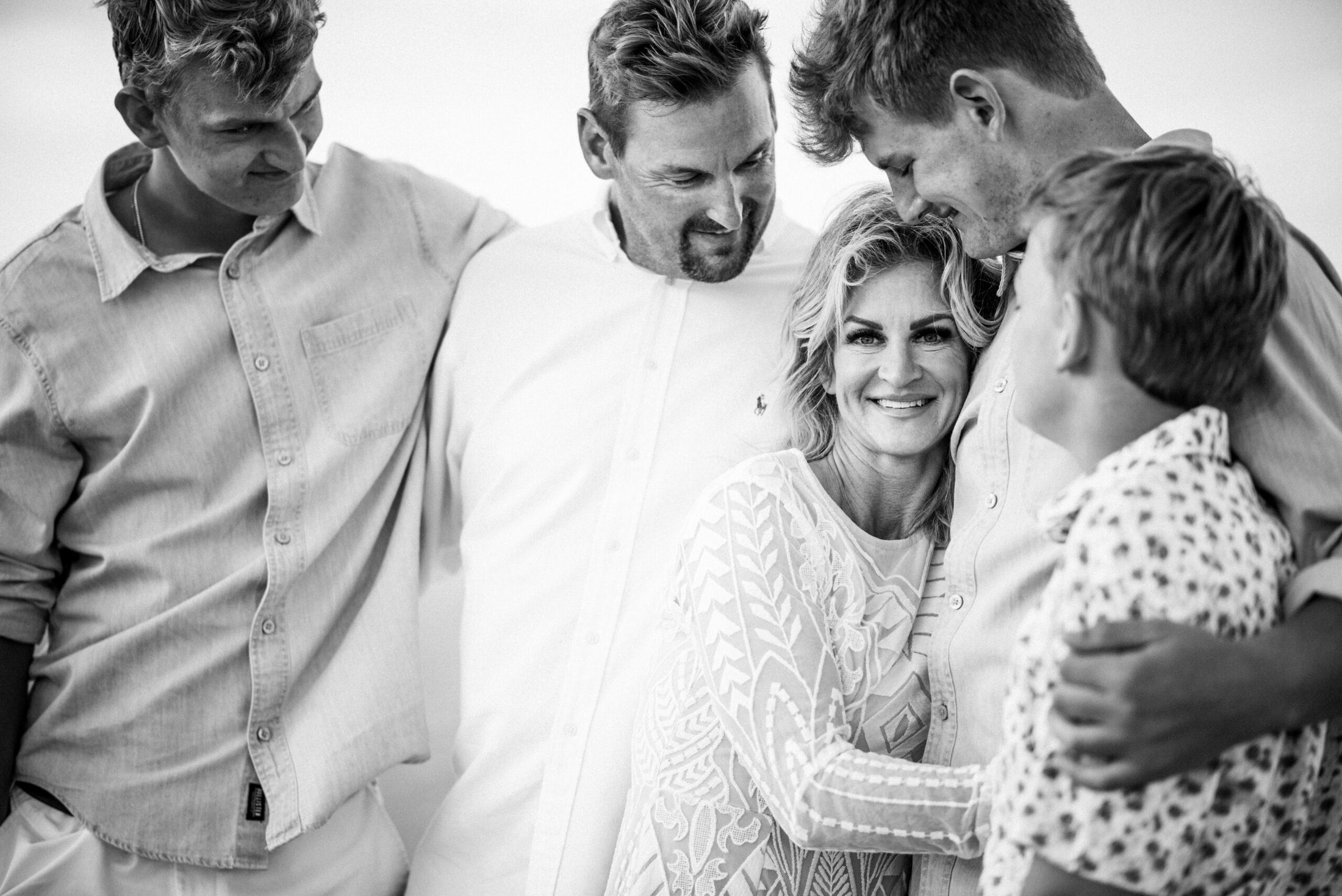 Family smiling and hugging while everyone looks at the mother in a family photoshoot in Jacksonville FL