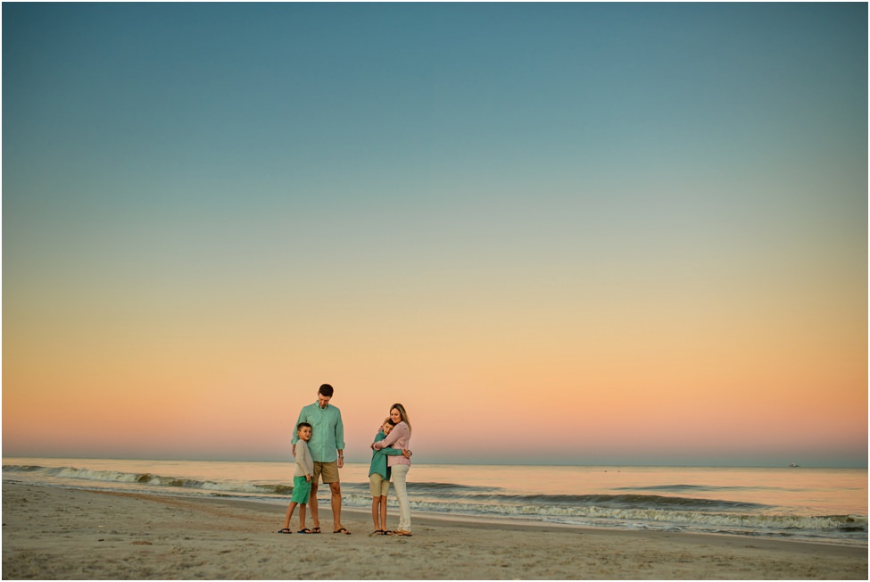 Family posing for a photo on the beach shore at dusk in a family photoshoot in Jacksonville FL