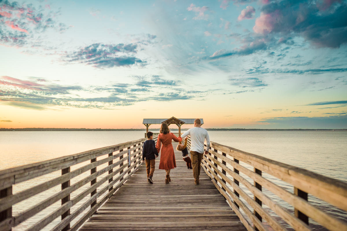 Family holding hands walking on the pier in a family photoshoot in Jacksonville FL