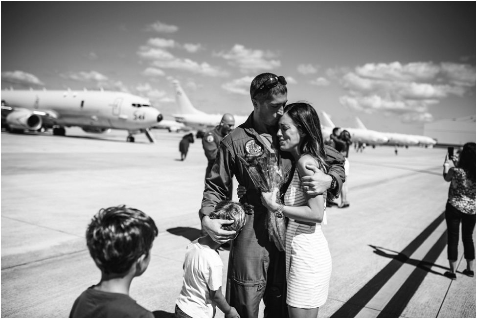 Parents hugging with children standing around them at an airport for a family photoshoot in Jacksonville FL