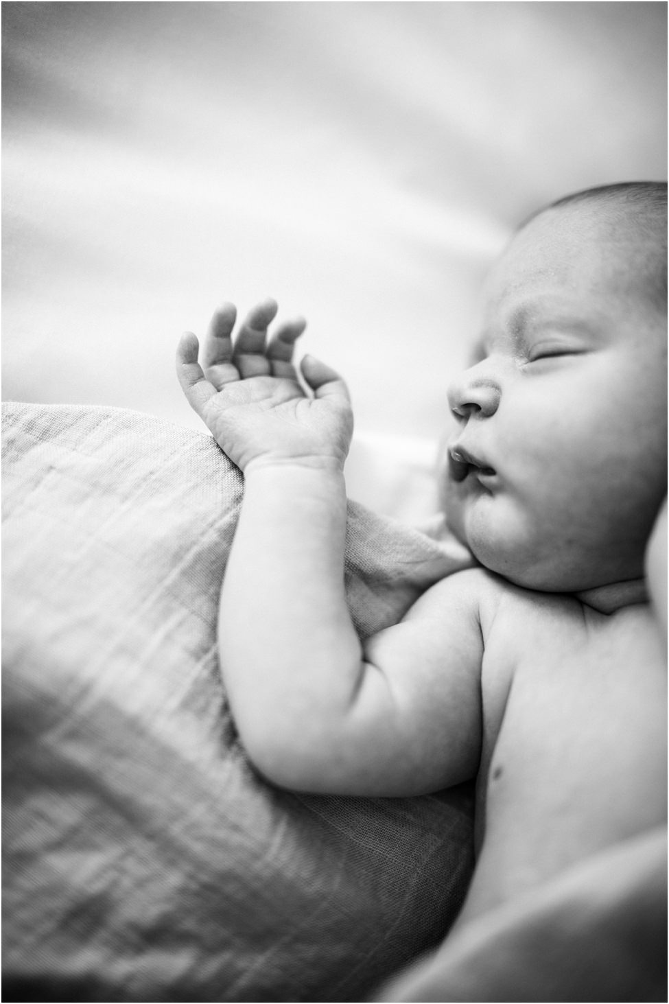 “Black and white close-up of newborn baby sleeping peacefully on bed during in-home lifestyle session in Jacksonville”