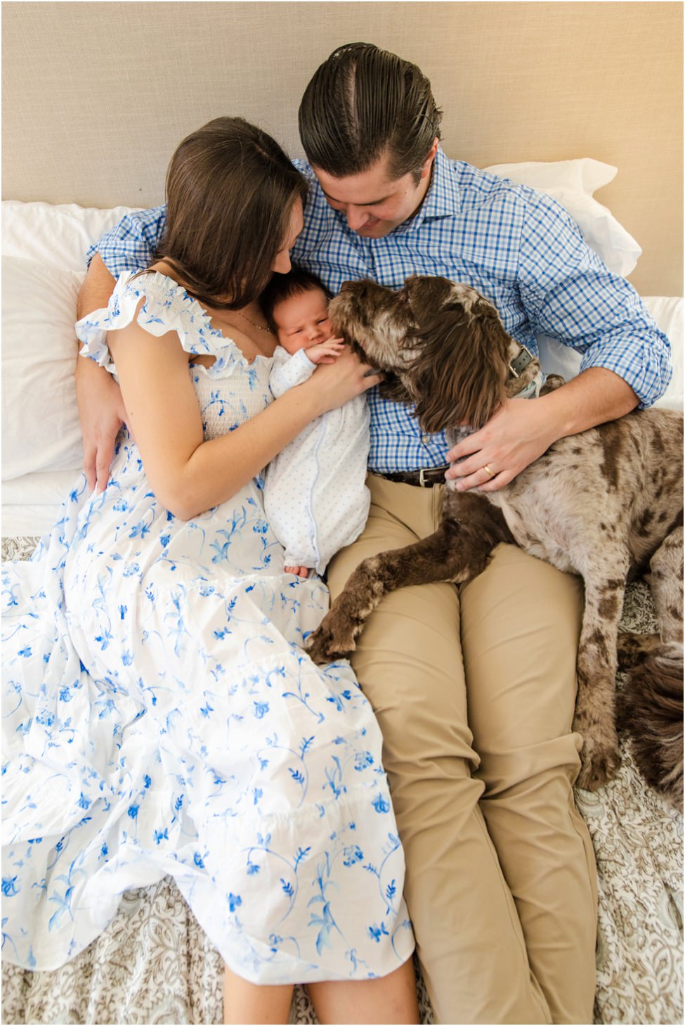 “Family snuggled on bed with newborn baby and their dog during a relaxed in-home lifestyle session in Jacksonville, photographed by Monika Colichio”