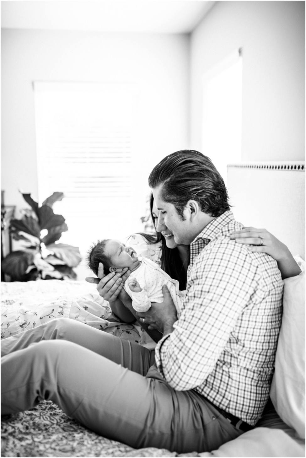 “Joyful parents cuddling their newborn on a bed during an intimate lifestyle session in Jacksonville, captured by Monika Colichio Photography”