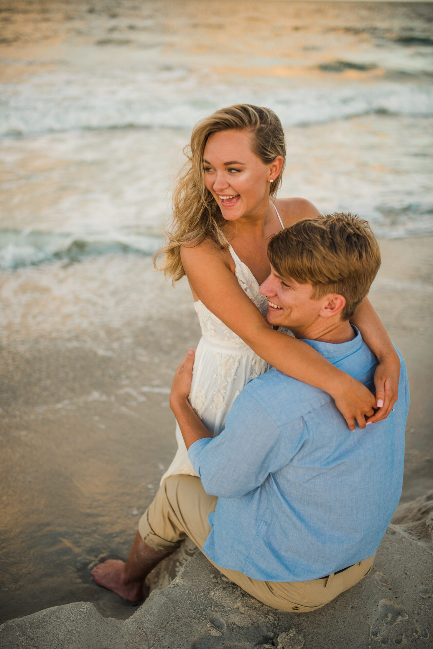 couple holding each other laughing on the beach shore in a jacksonville couples photoshoot