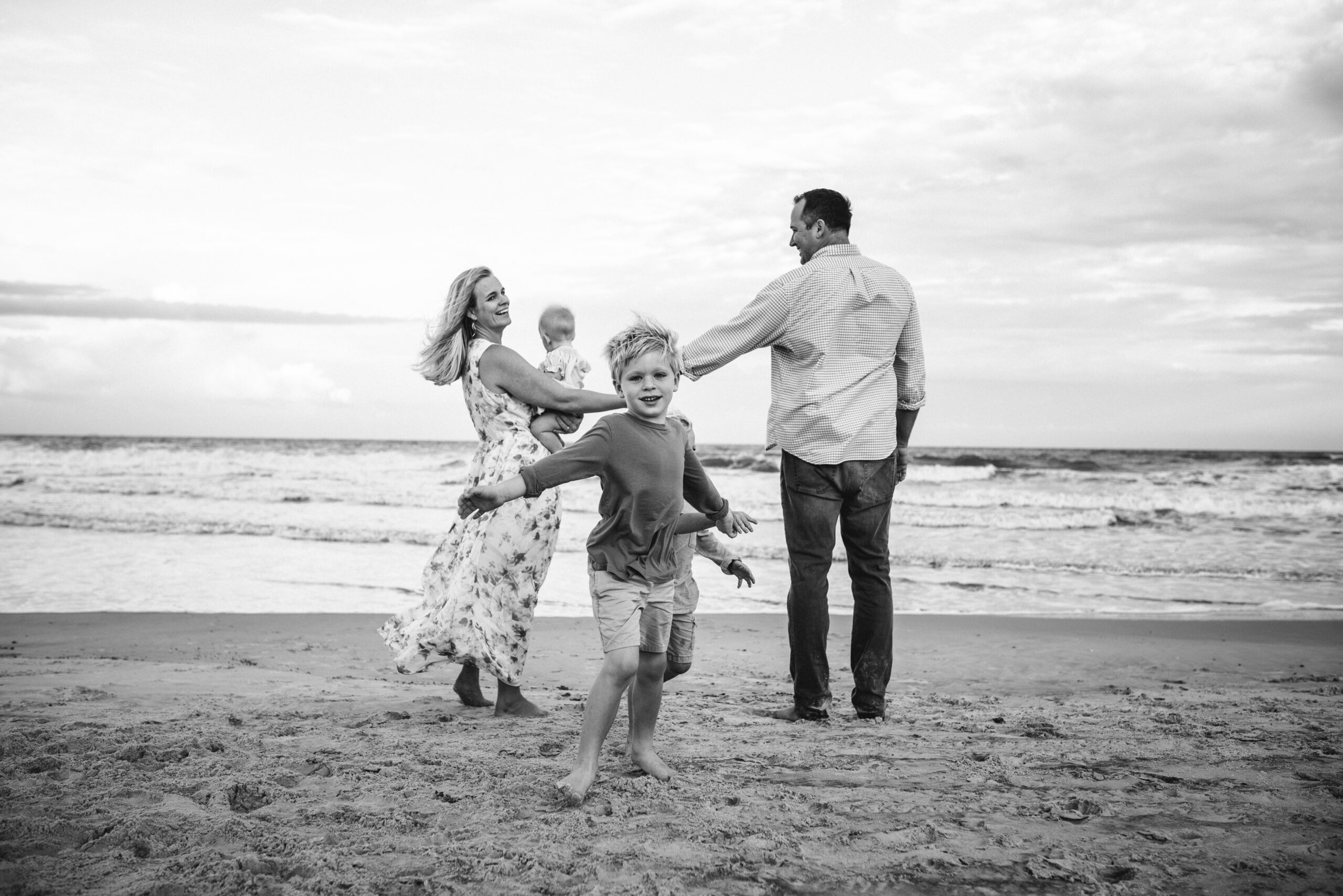 Big brother running around his family on Neptune Beach family session by Jacksonville family photographer