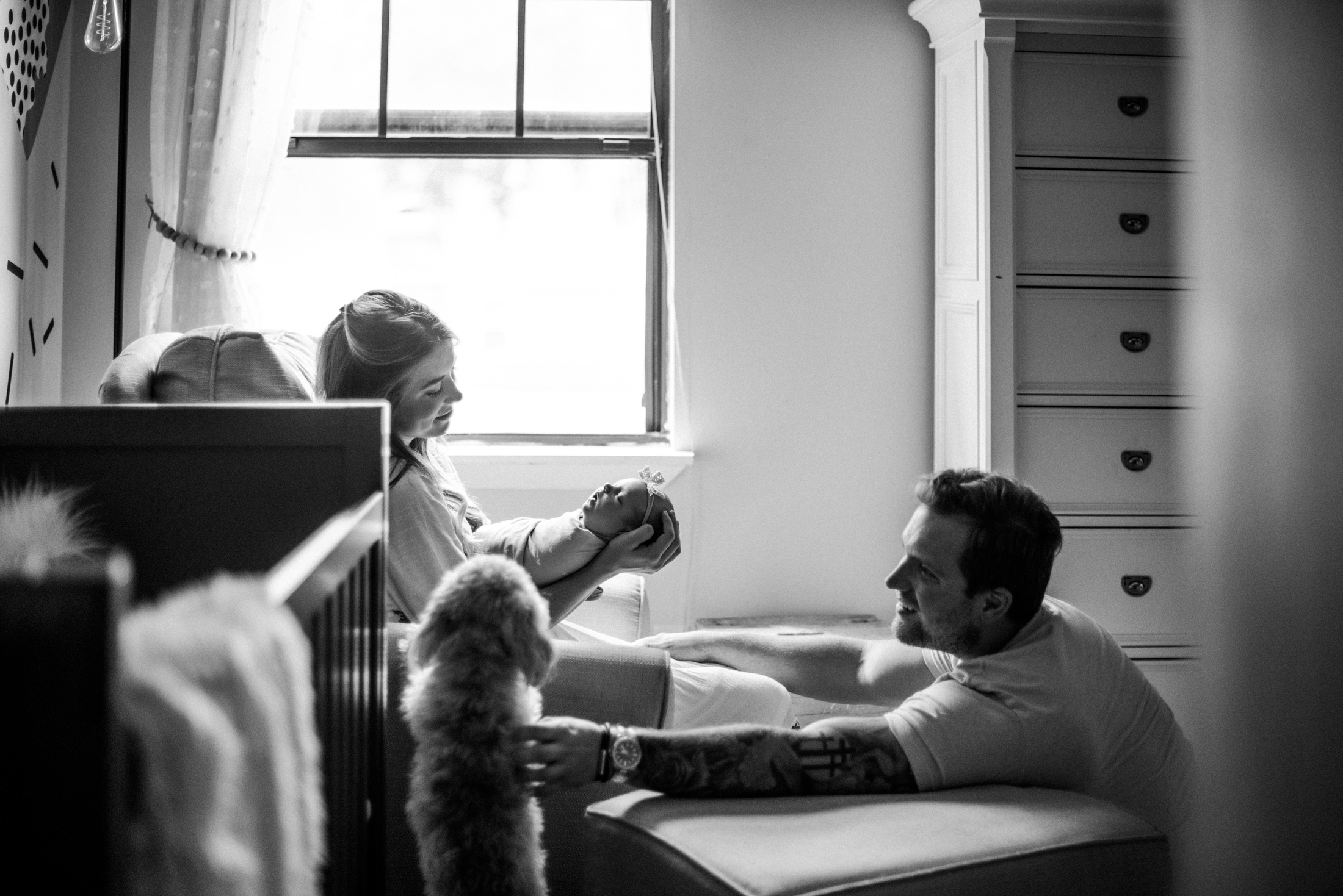 Emotive moment of parents enjoying first days at home with their newborn baby and their dog as a white and black portrait by Jacksonville newborn photographer