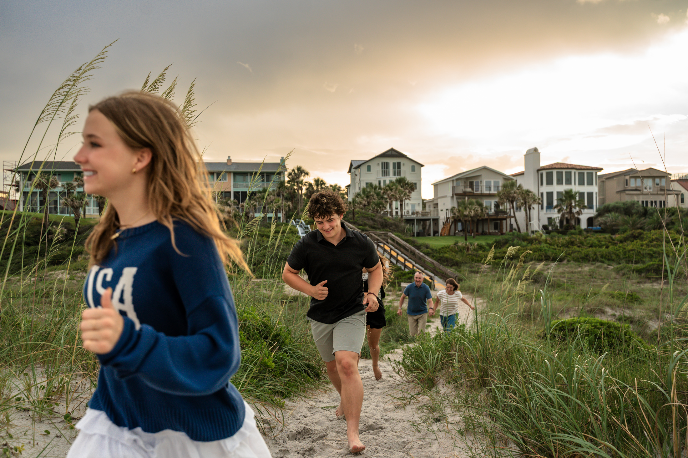 teenagers kids running toward the beach at their Neptune beach sunset family session by Jacksonville family photographer Monika Colichio