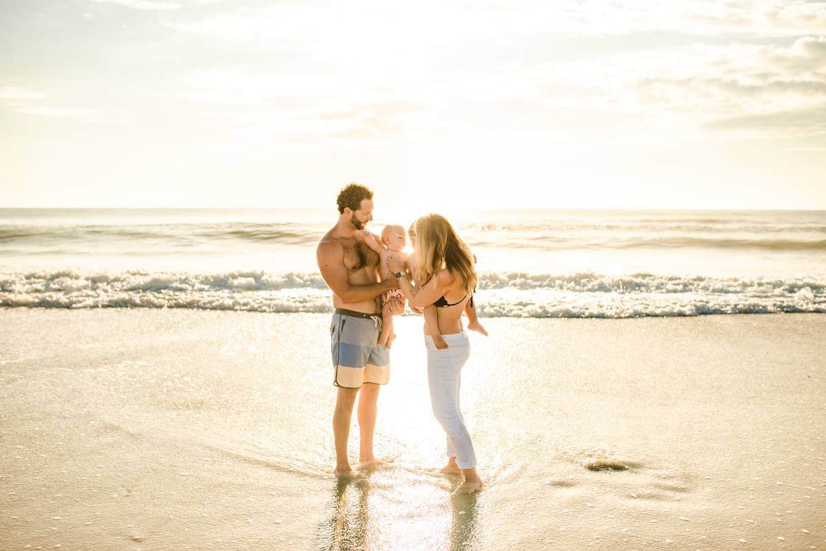 Family posing for photo on the beach with a small child in a family photoshoot in Jacksonville FL