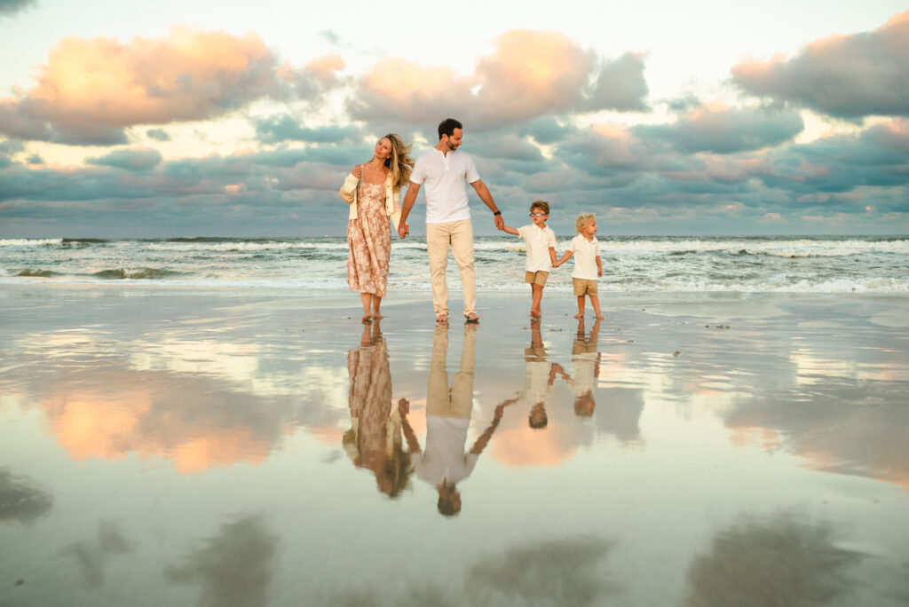 Family walking on the beach shore with small children posing for family photo in a family photoshoot in Jacksonville FL
