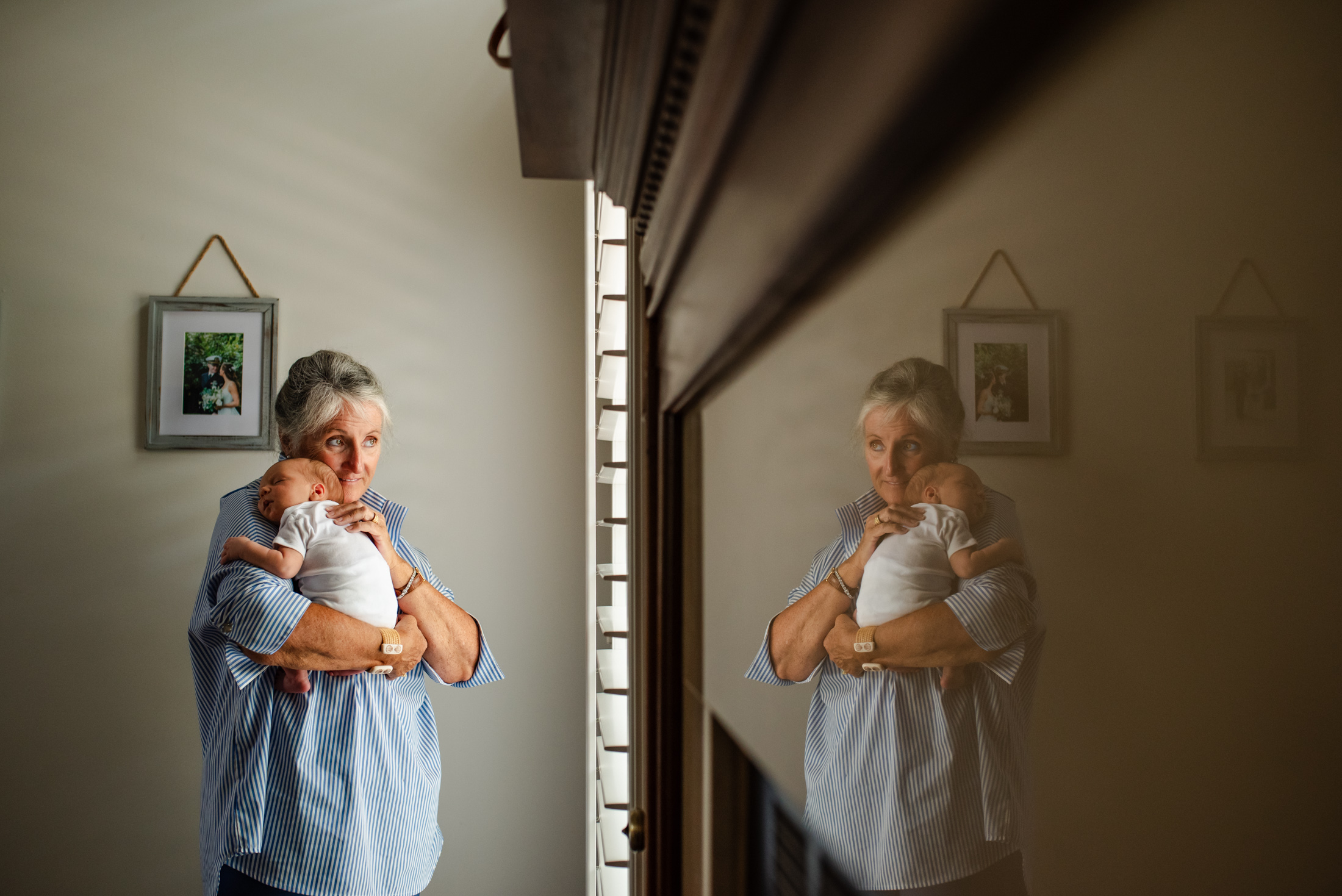 Emotive capture of grandma holding her new grandson with beautiful reflection of them together by Jacksonville newborn photographer MColichio Photography