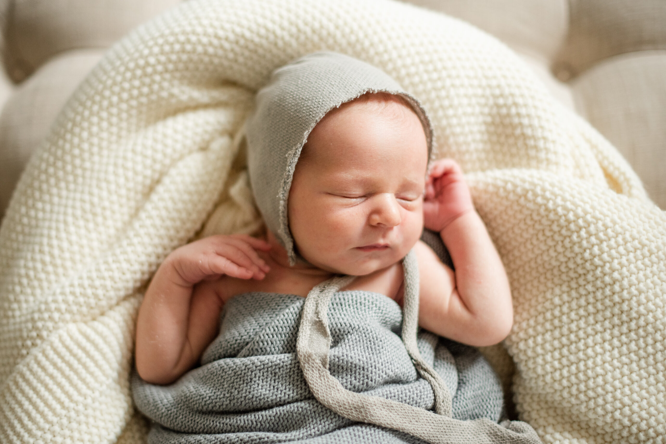 Natural portrait of peacefully sleeping baby in bonnet and a wrap during at home newborn session by Jacksonville baby photographer Monika Colichio