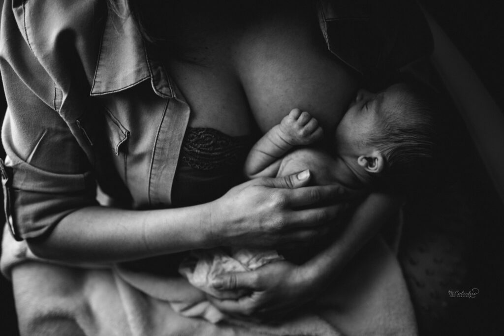 Emotive black and white image of a mother breastfeeding her newborn, captured by a Jacksonville newborn photographer