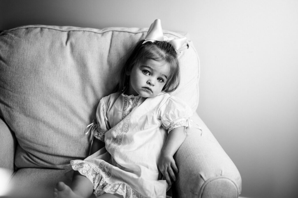 Soulful portrait of a little girl sitting by the window in her chair captured by Jacksonville family photographer