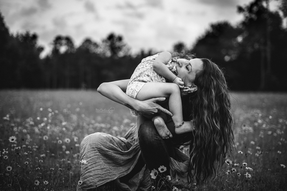 Heartwarming black and white portrait of a mother and daughter hugging and smiling outdoors, captured by a Jacksonville family photographer