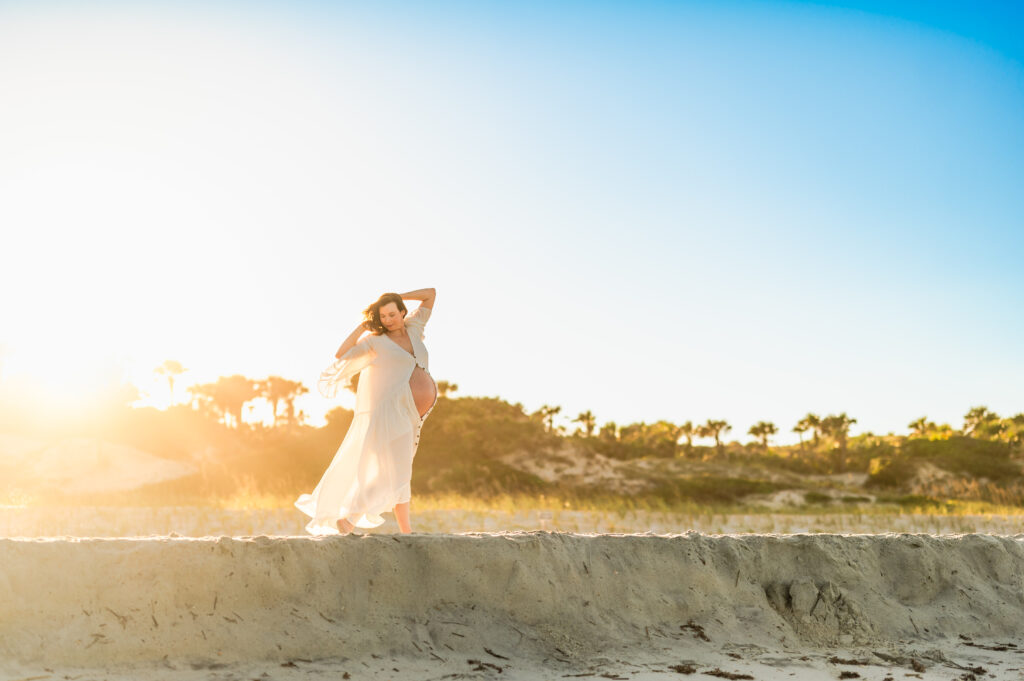 Expecting momma stretching at the sunset beach pregnancy session by Jacksonville maternity photographer. Sunset beach maternity photos Jacksonville